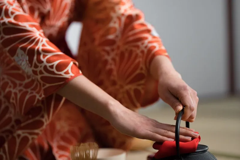 Person in a kimono preparing tea in a traditional Japanese ceremony