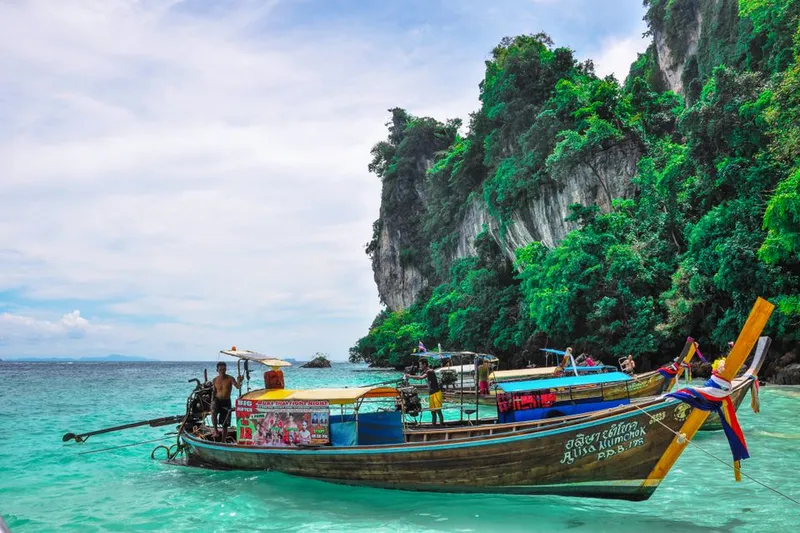 Longtail boat beside limestone cliffs in Thailand